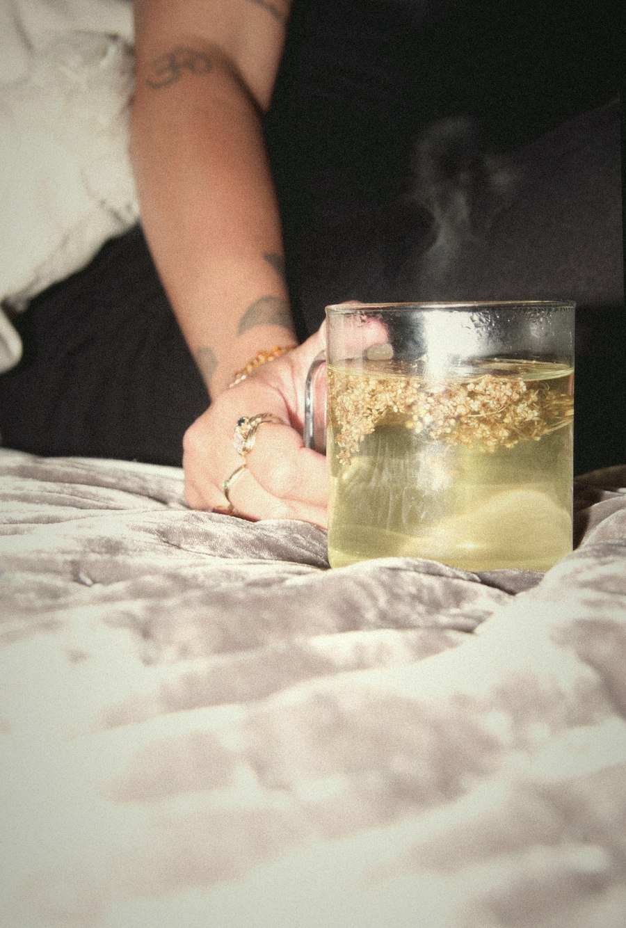 A steaming cup of flower tea on a bed